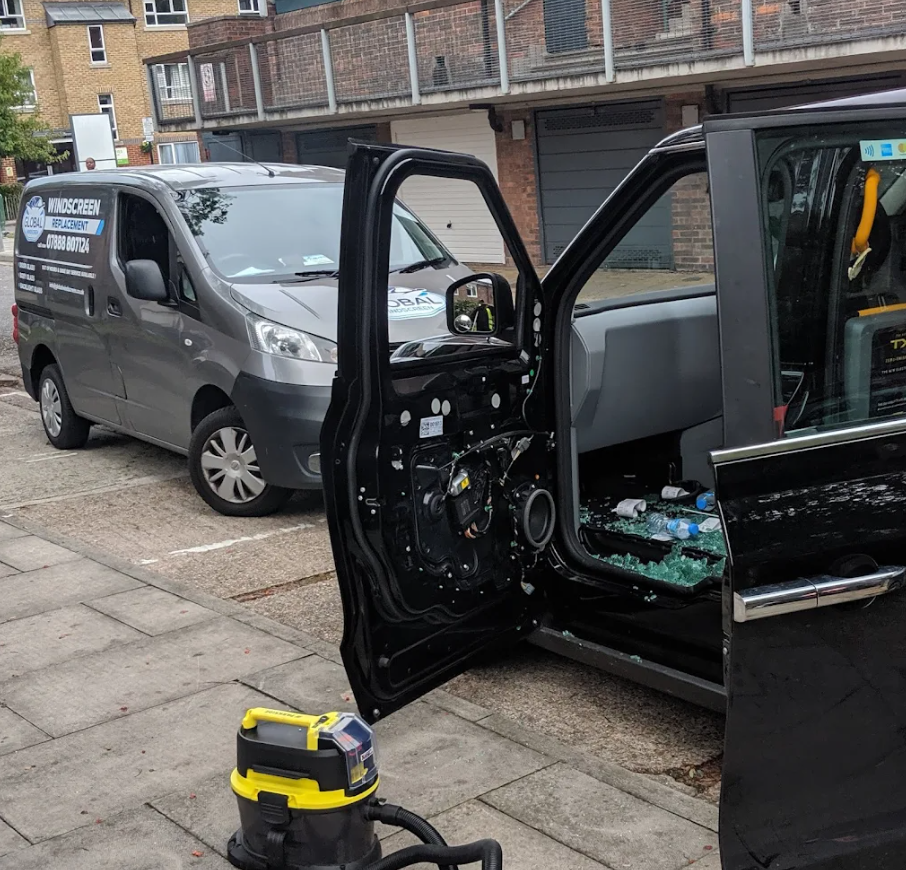 Side window replacement in progress with Global Windscreen van — door panel exposed and shattered glass being cleared